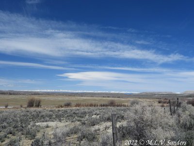 ranch with its fence, hay field surrounded by irrigation ditches. In the far background the Wind River Range